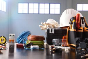 Composition with tools and electrical equipment on black table and industrial ship background. Horizontal composition. Front view.